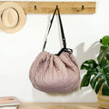 MiniDream toy storage bag hanging by its black shoulder strap from a wooden wall peg.