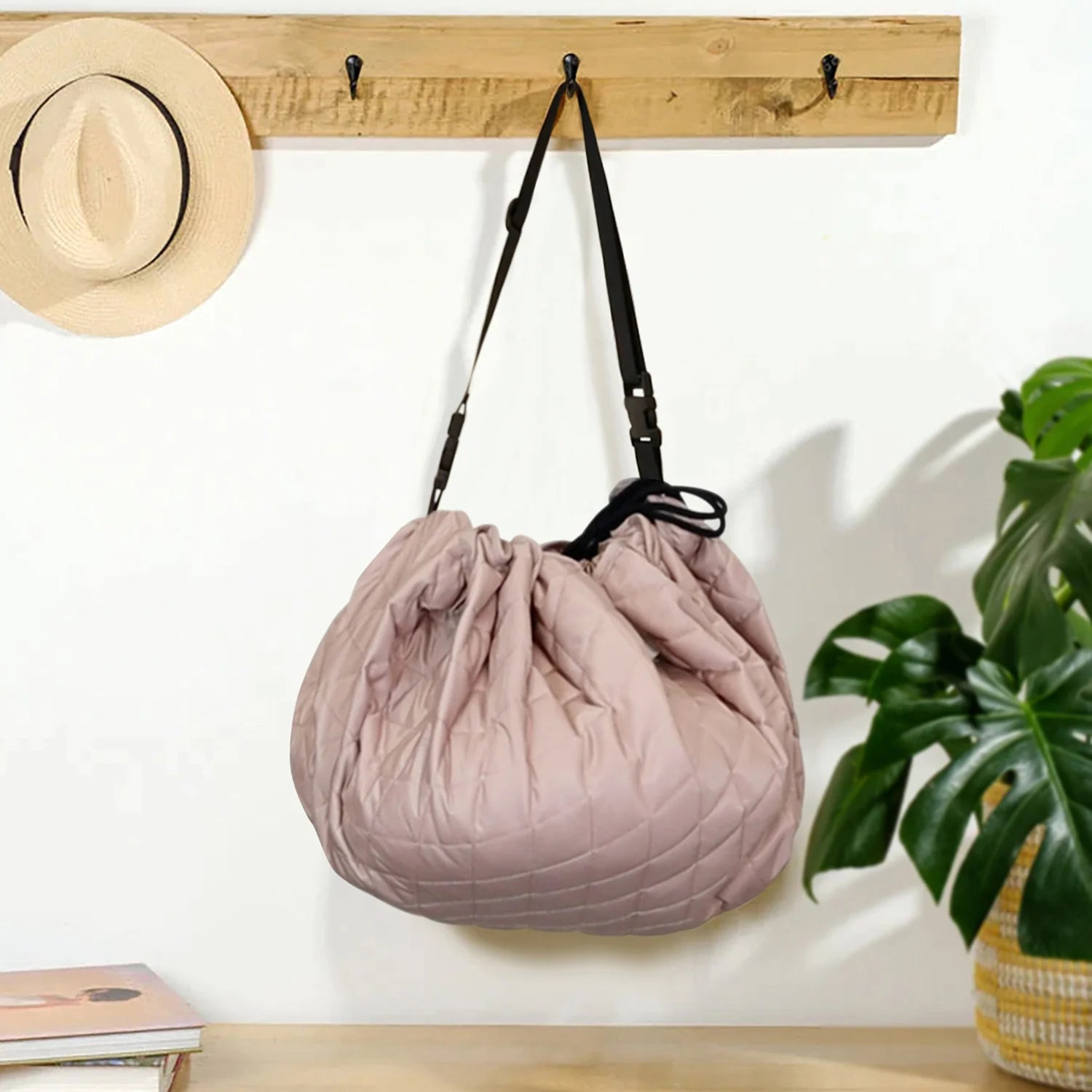 MiniDream toy storage bag hanging by its black shoulder strap from a wooden wall peg.