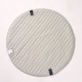 Solid sage green reverse side of the circular playmat laid flat, highlighting its quilted fabric texture.