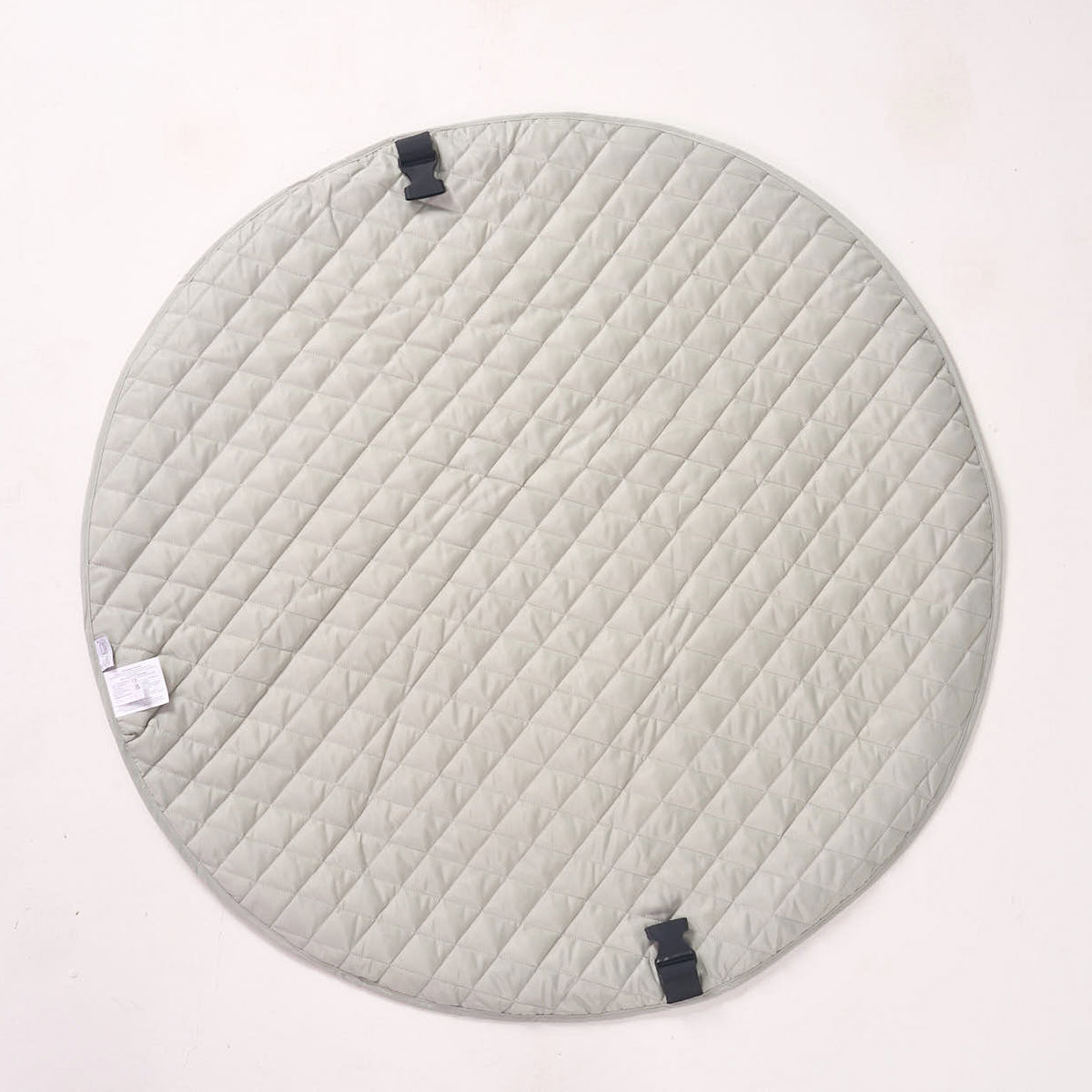 Solid sage green reverse side of the circular playmat laid flat, highlighting its quilted fabric texture.