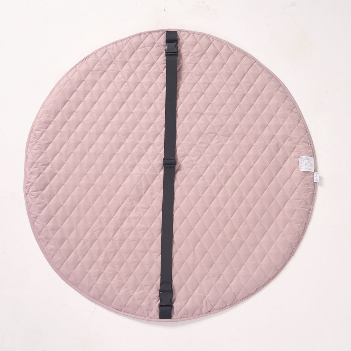 Solid pink reverse side of the MiniDream playmat laid flat, showing an integrated black carrying strap across the center.