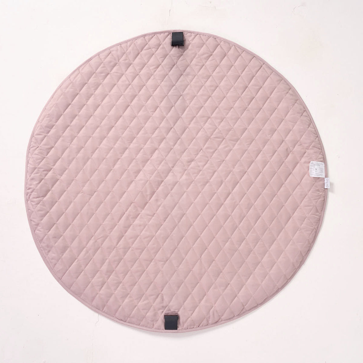 Solid pink reverse side of the MiniDream playmat laid flat, highlighting the quilted fabric texture.