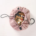 MiniDream playmat partially cinched together into a storage bag holding wooden toys.