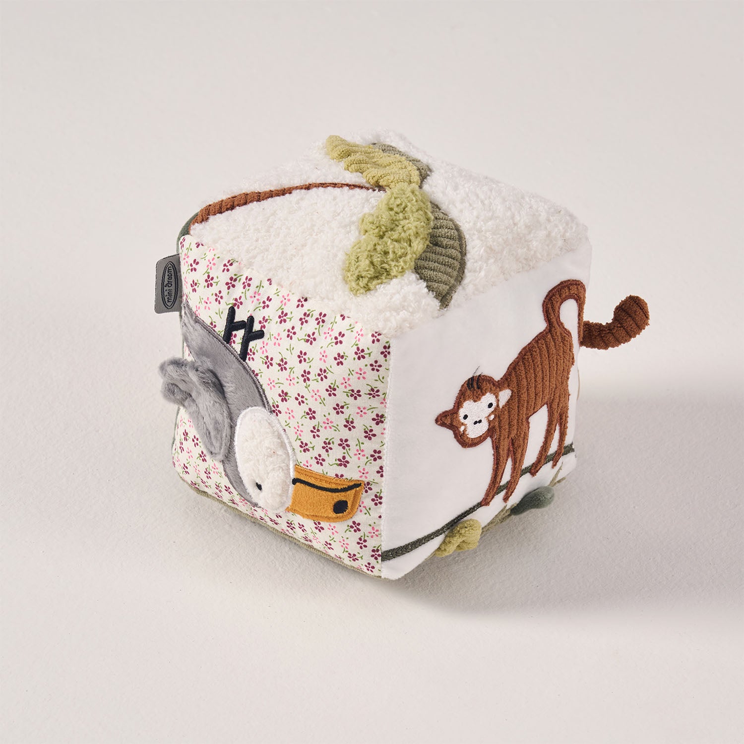 Angled view of the MiniDream sensory learning toy displaying the monkey design along with soft, crinkly jungle leaves for tactile exploration.