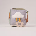 Side view of the MiniDream baby activity cube highlighting a soft sensory cloud applique with hanging textured knots.
