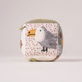 Side view of the MiniDream Jungle Soft Activity Cube displaying a plush toucan bird set against a soft pink and patterned fabric background.