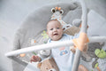Newborn lying on the MiniDream play mat, reaching for hanging jungle toys.