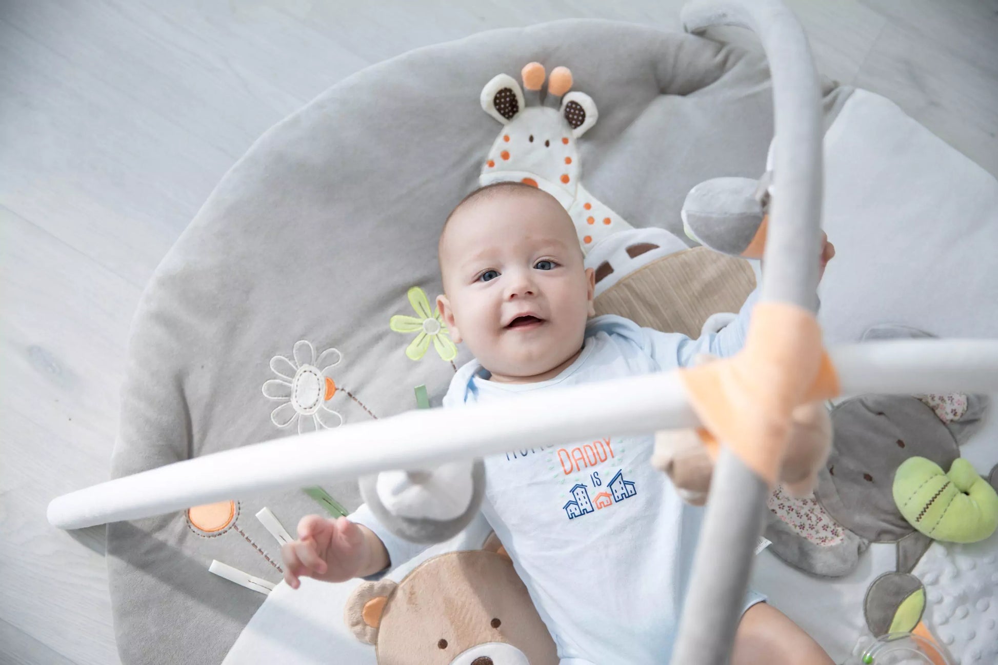 Newborn lying on the MiniDream play mat, reaching for hanging jungle toys.